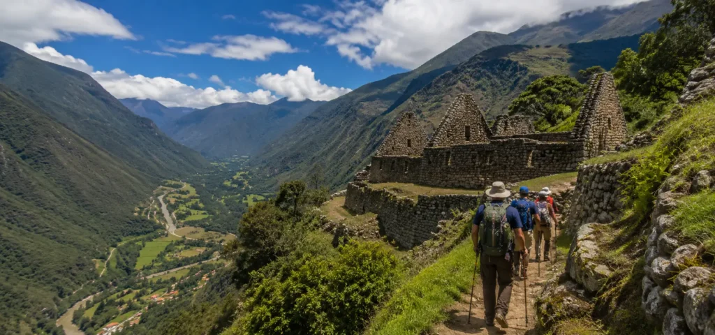 Hikers walking past the Llactapata ruins with the green Urubamba Valley stretching below